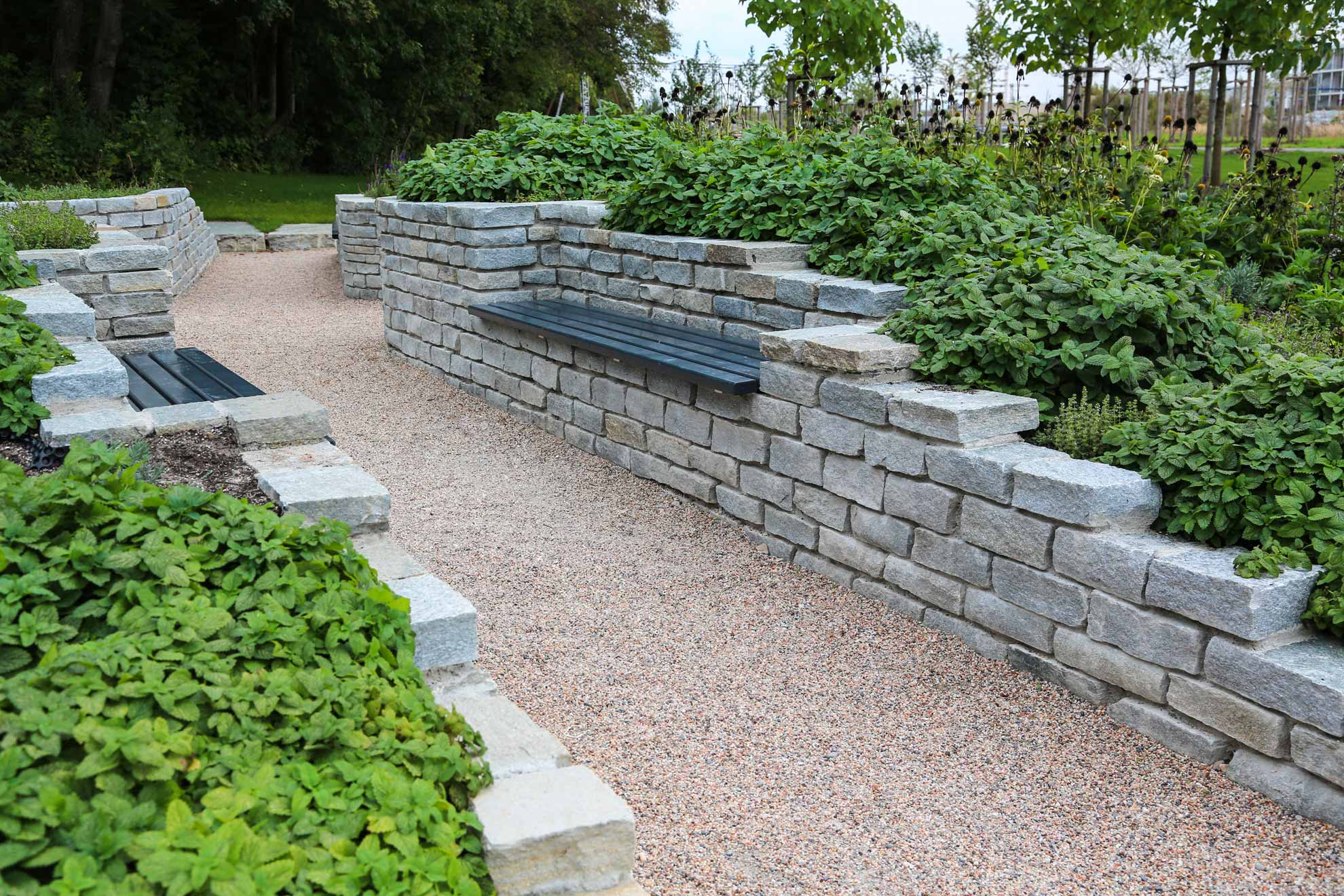 Steinmauer am Weg mit Sitzbank